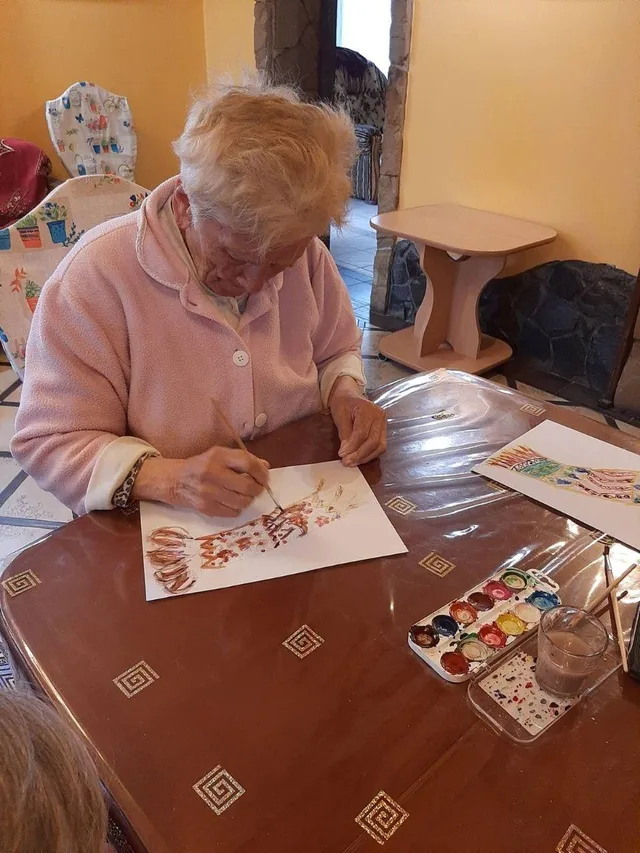 Мешканка працює над малюнком, уважно добираючи кольори.