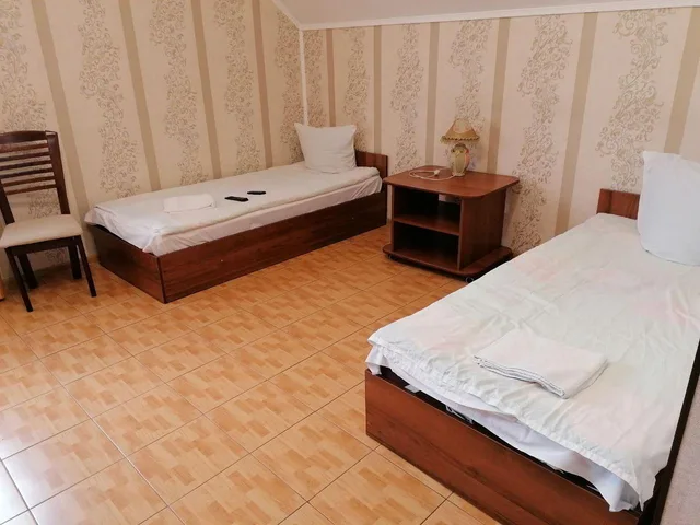 Два ліжка стоять поруч у світлій кімнаті з дерев’яною підлогою.