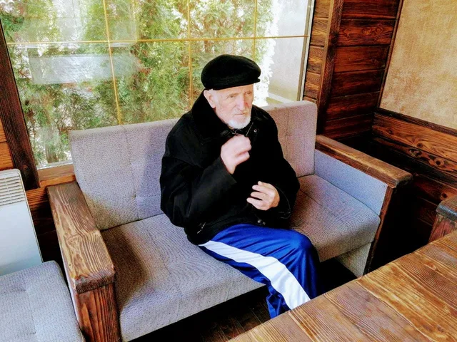 Мешканець відпочиває за столом у затишному куточку веранди.