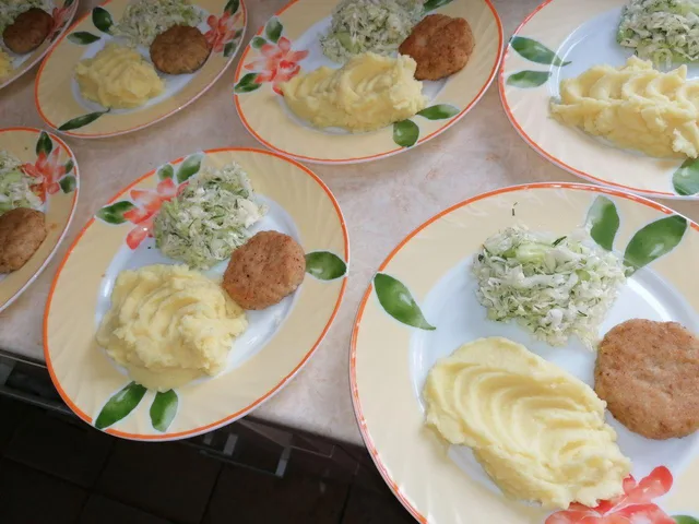 На столі розставлені тарілки з гарніром, овочами та основною стравою.