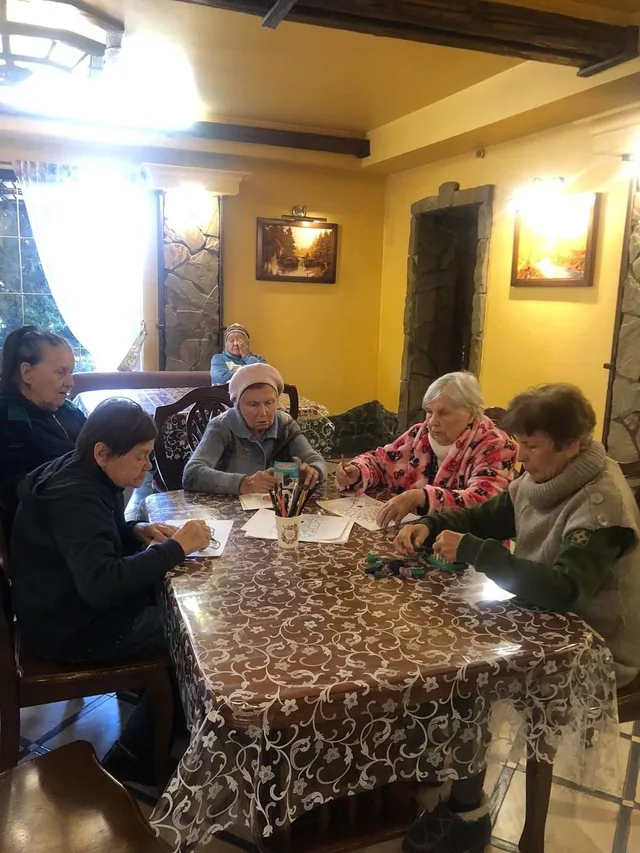 Мешканці сидять за великим столом під час спільного обіду.
