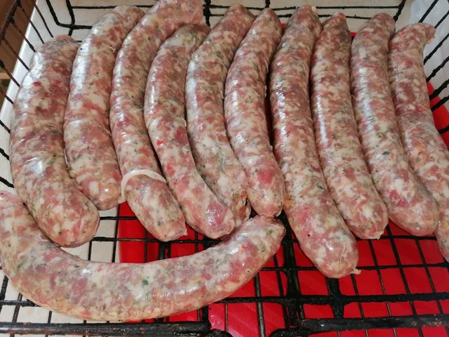 На решітці над жаром готуються ковбаски.