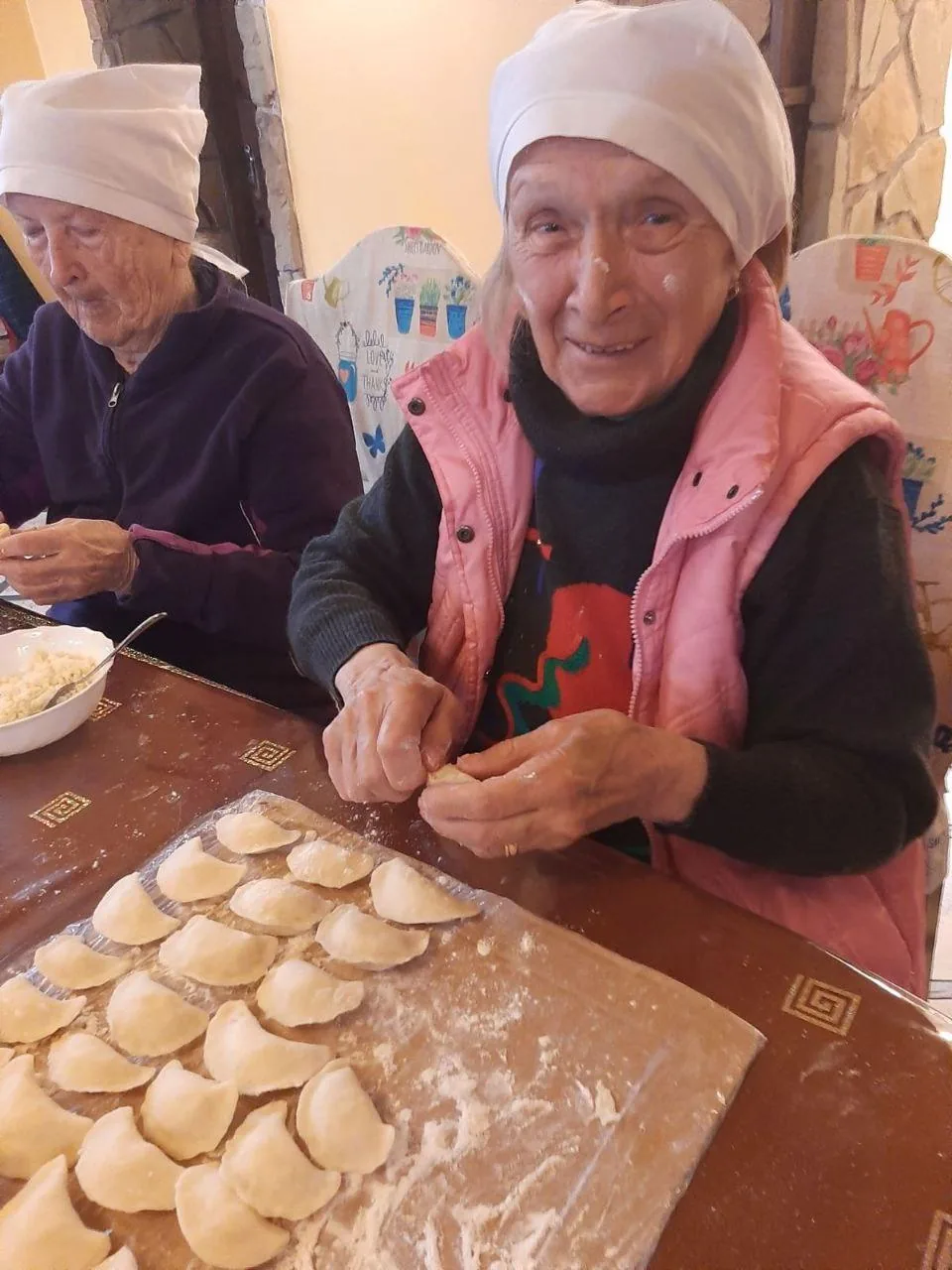 Мешканці разом ліплять вареники й викладають їх рядами на дошці.